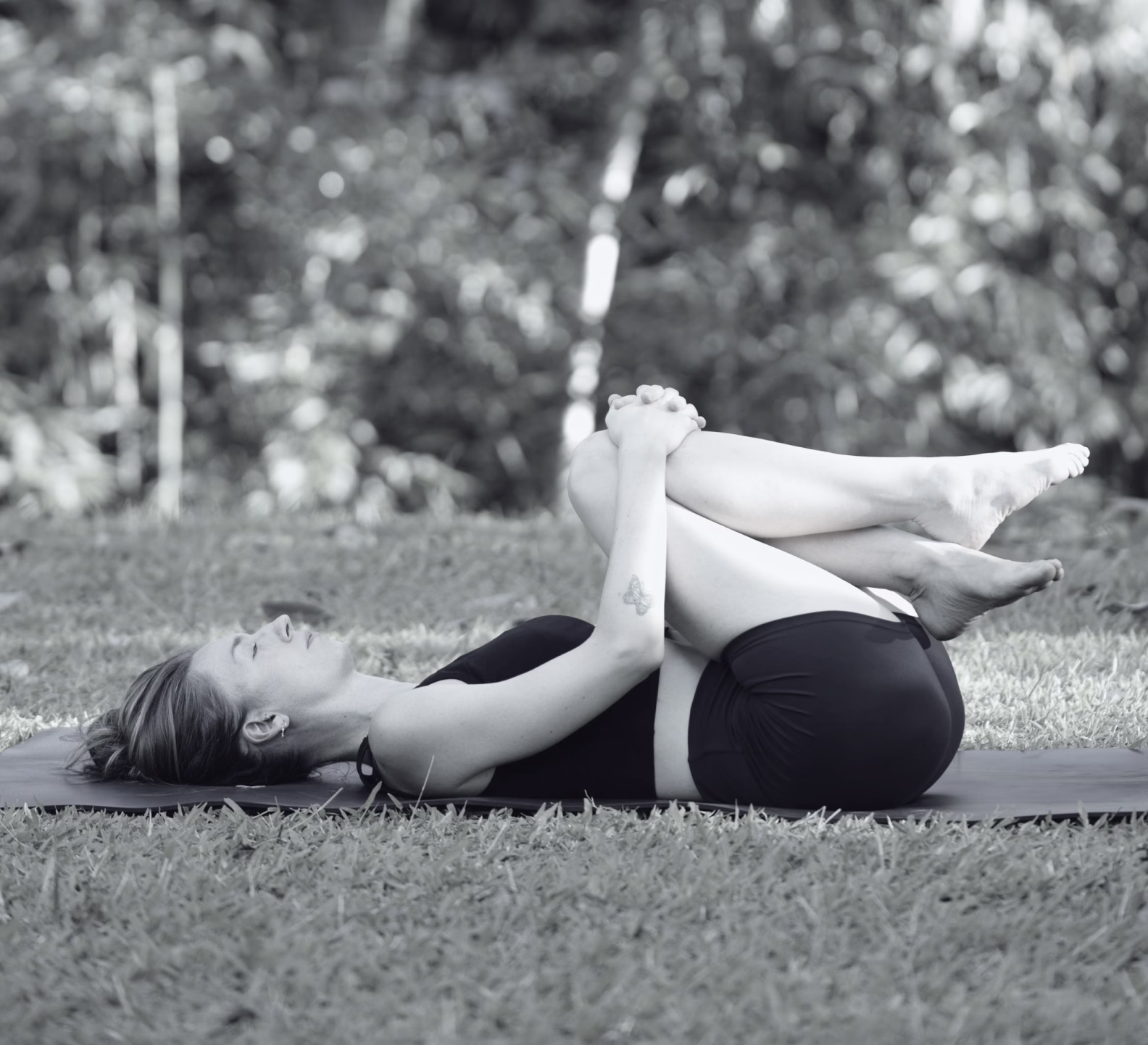 Joanna lying on a yoga mat hugging the knees to her chest